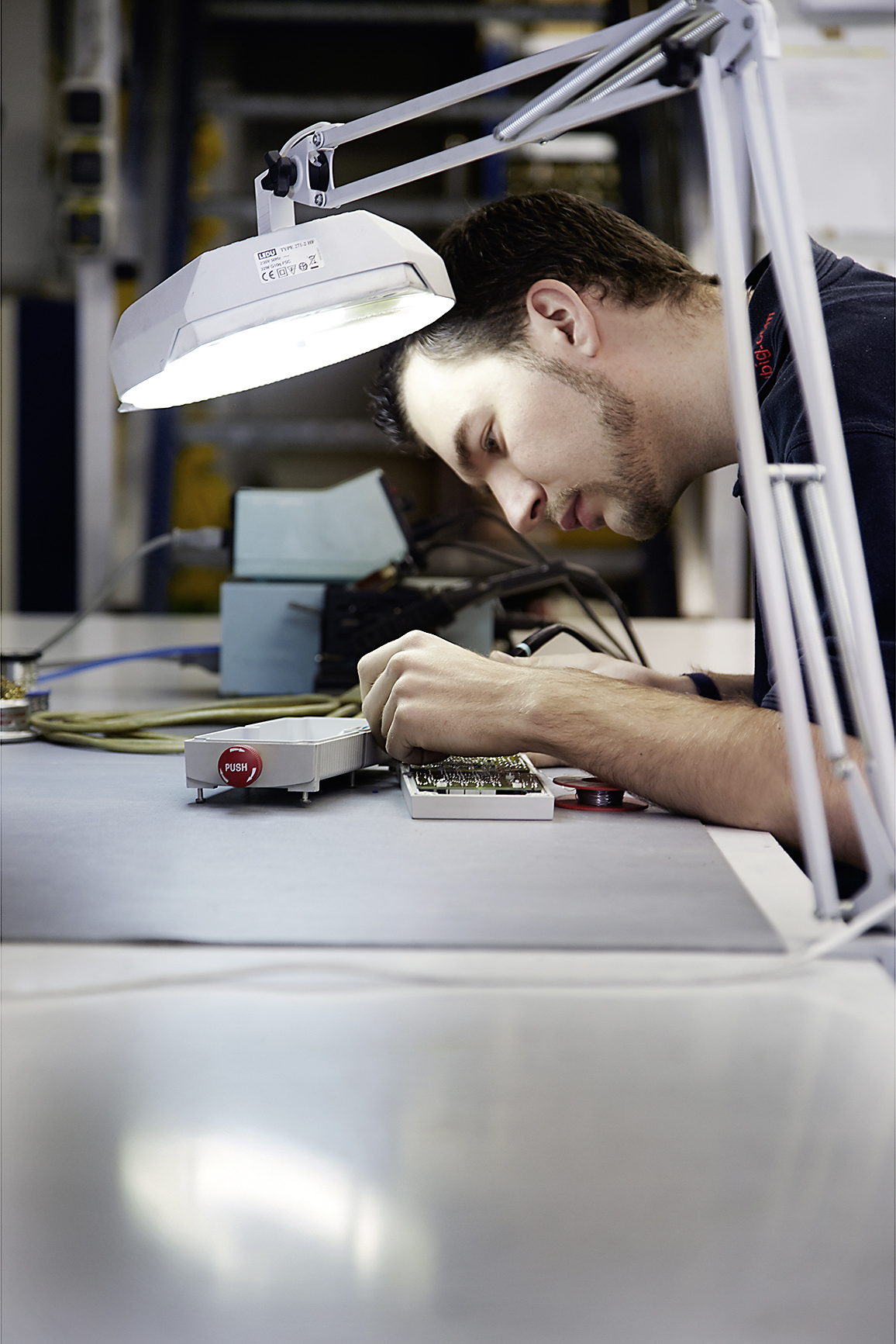 Mitarbeiter bei der Feinmontage unter der Lupenlampe bei RÜBIG Engineering – Industriefotografie Roland Wimmer